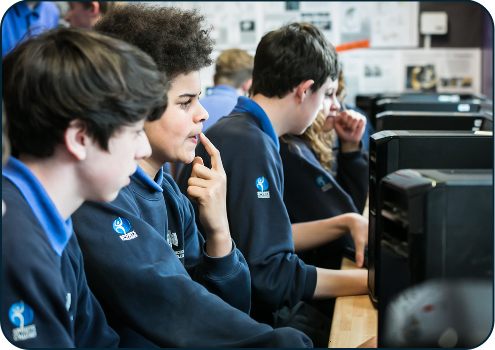 a group of people sitting at a desk looking at a computer